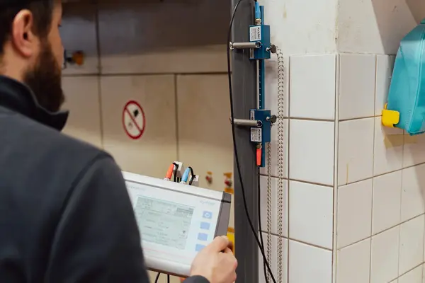 Maschinendiagnose mit Aufschnall-Ultraschall-Durchflussmesser: Messung an einer Rohrleitung, Auswertung am Tablet.